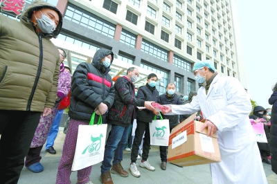 昨天，武漢協和醫院西院區31名重症患者治愈出院，其中北京醫療隊3個病區共出院16人。醫生們向出院患者贈送口罩，叮囑他們注意個人防護。  本報記者 和冠欣攝
