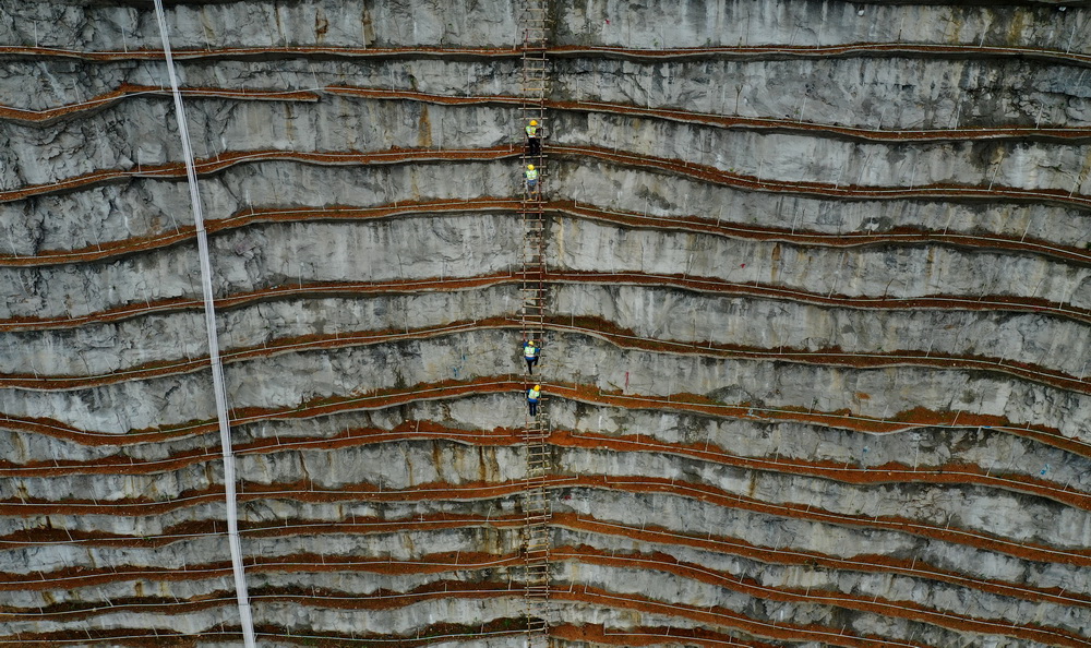 3月22日，在廣西柳州市樓梯山山體復綠工程施工現場，工人沿著扶梯爬上陡峭的山體作業（無人機照片）。